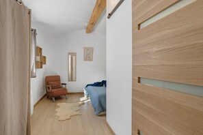 A bedroom with a bed, a chair, a rug, and a wooden wardrobe.