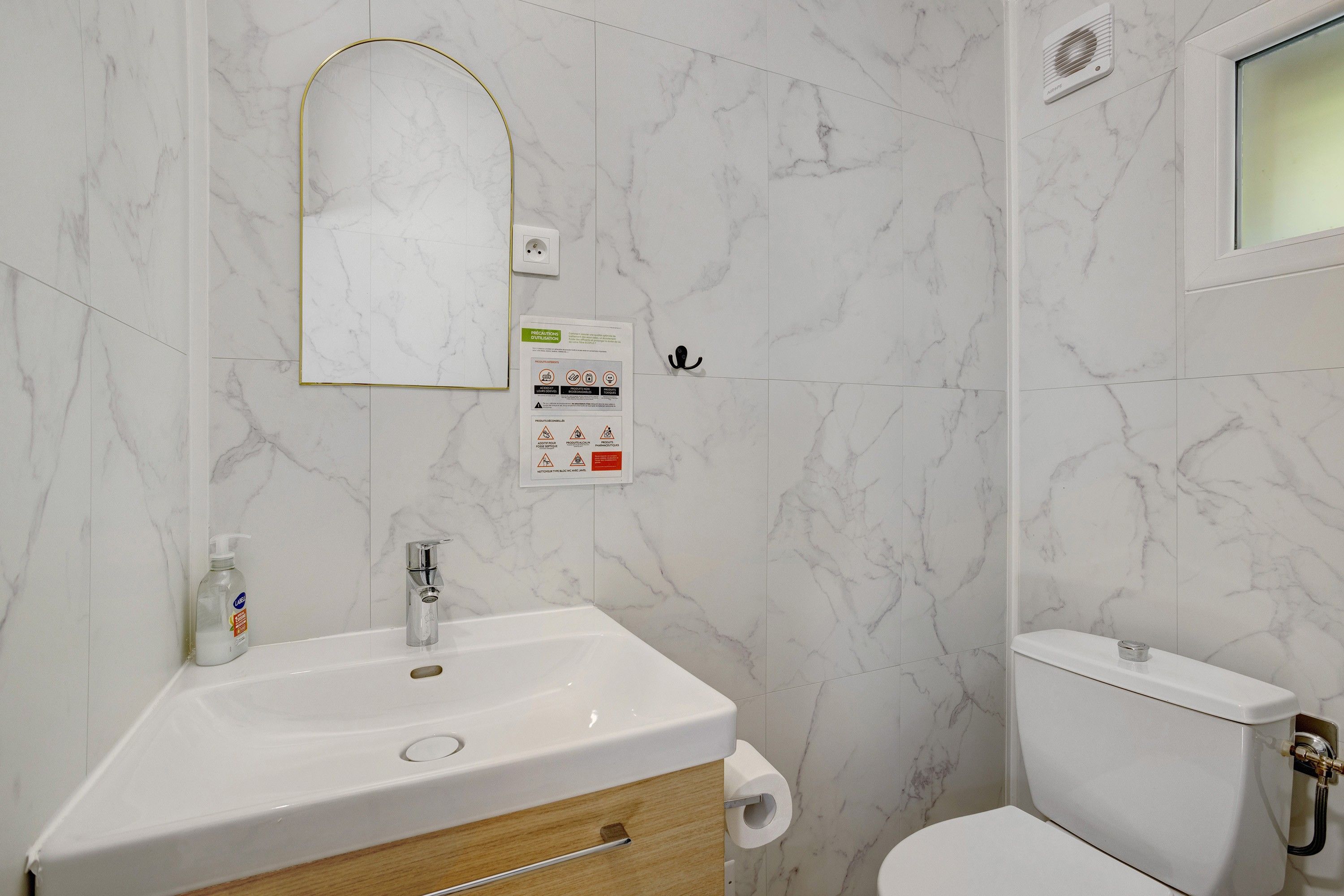 Un bagno con lavandino, specchio e WC bianchi.