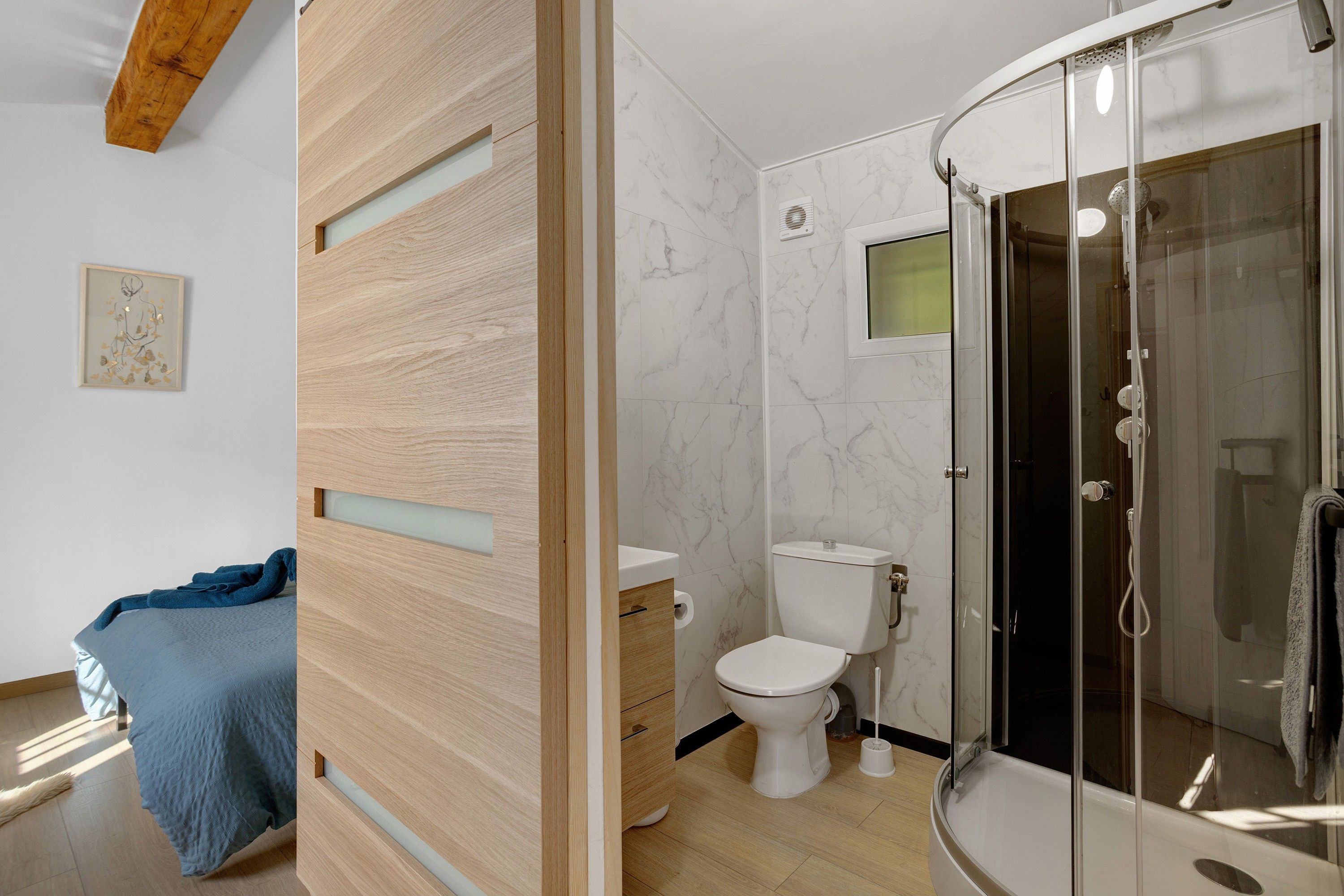 Une salle de bain moderne avec une douche à parois de verre, des toilettes et un meuble-lavabo en bois.