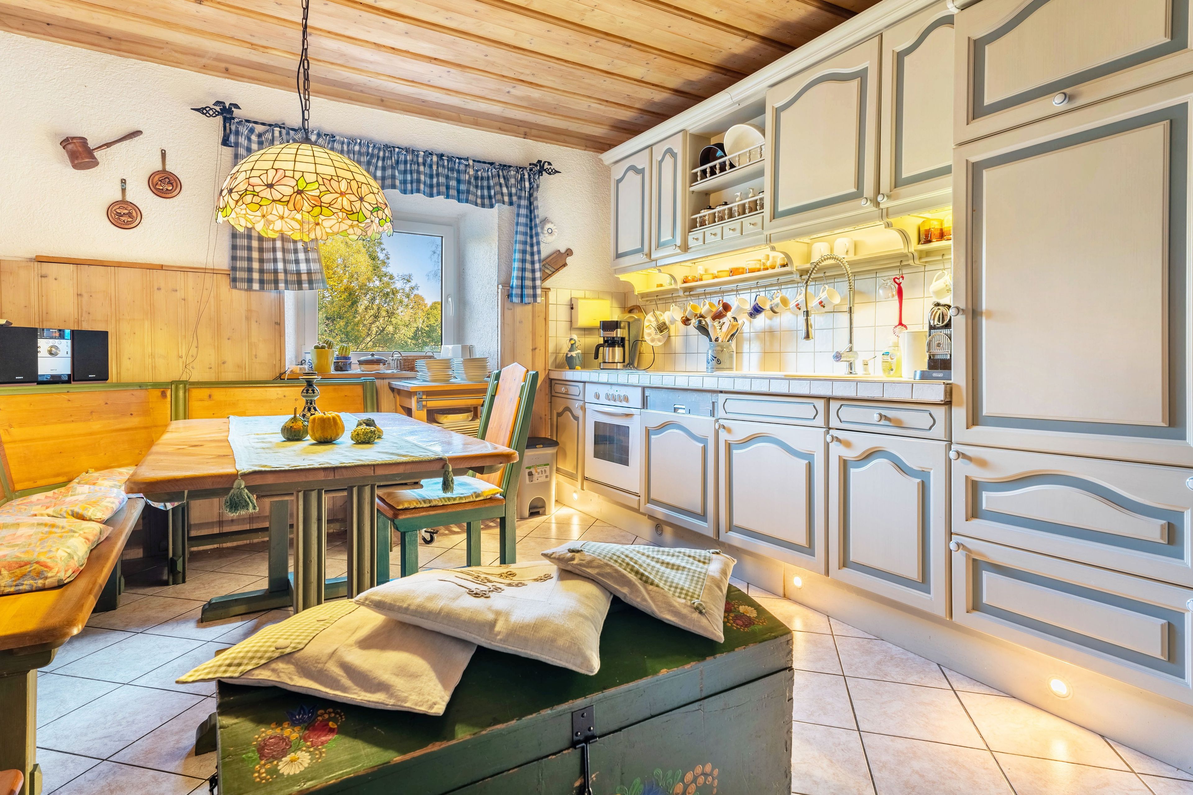 A cozy kitchen with wooden cabinets, a dining table with chairs, and a hanging light fixture.
