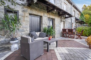 A stone building with a patio area featuring outdoor furniture and potted plants.