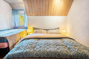 A bedroom with a bed, a window with curtains, a lamp, and a wooden ceiling. - Holiday Home Madlholz with Private Terrace and Garden (Geiersthal)