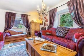 A cozy living room with a sofa, a coffee table, and a chandelier. - Holiday Home Madlholz with Private Terrace and Garden (Geiersthal)