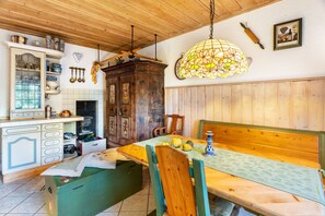 A rustic dining area with a wooden table, benches, and a stained glass light fixture.