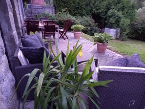 An outdoor patio with wicker furniture, potted plants, and a stone wall. - Holiday Home Madlholz with Private Terrace and Garden (Geiersthal)