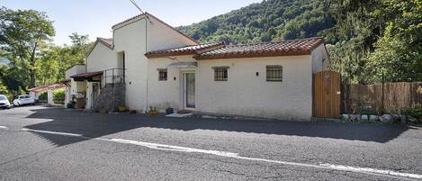 Un bâtiment à deux étages, doté d’un toit en tuiles, d’une allée en gravier et d’une clôture en bois.