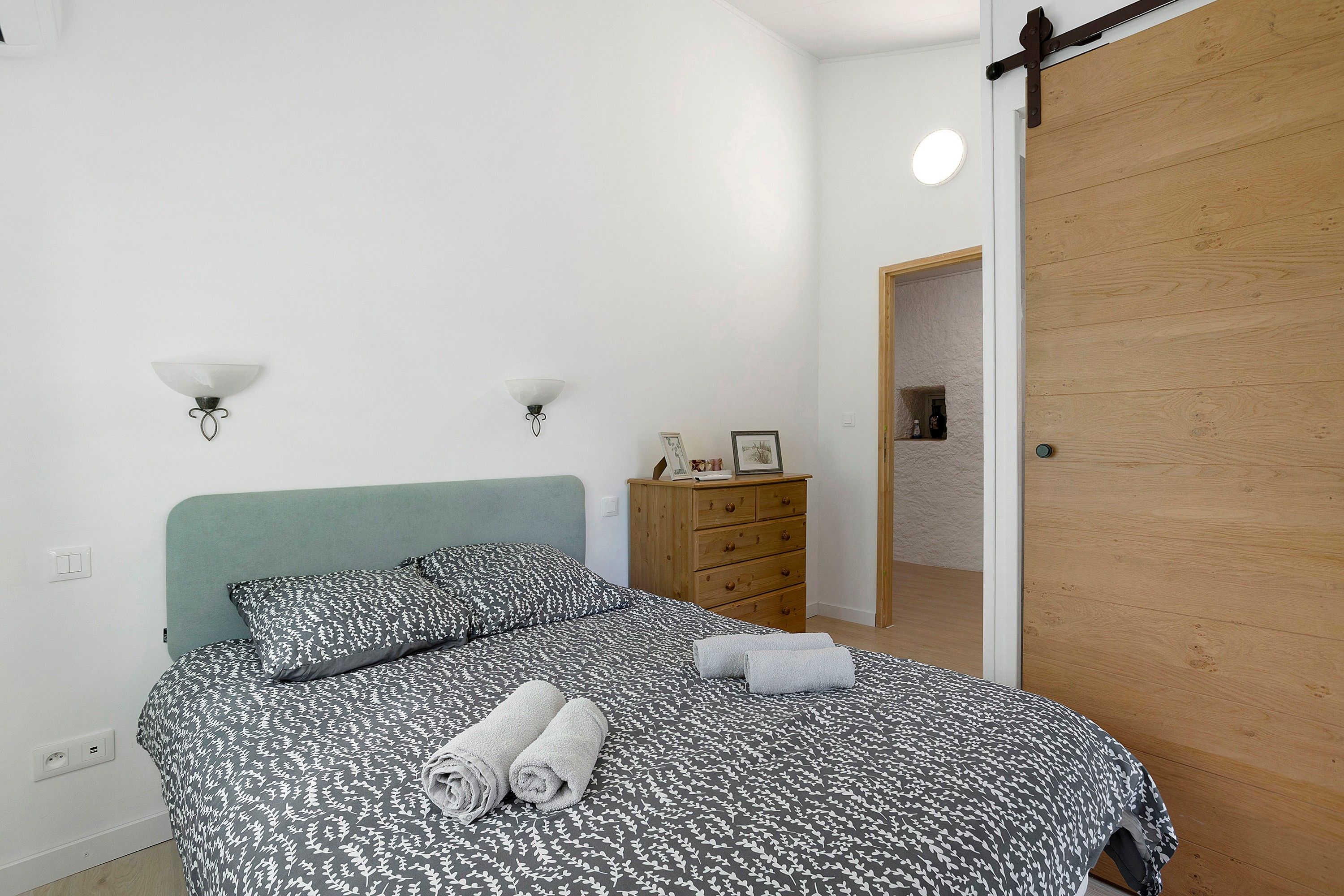 Een slaapkamer met een bed, een dressoir en een deur.