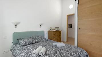 Een slaapkamer met een bed, een dressoir en een deur.
