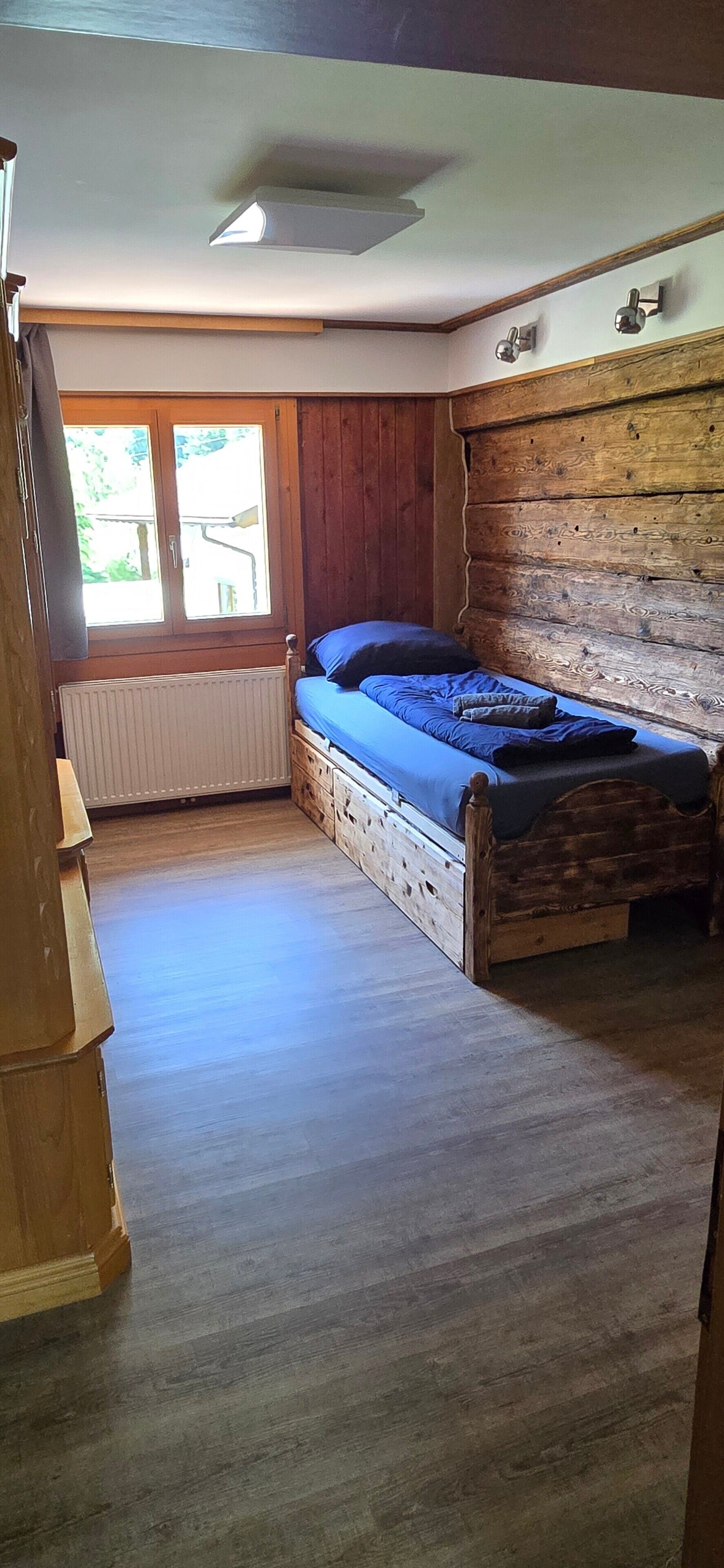 Un dormitorio con una cama de madera, una ventana con cortinas y un radiador.