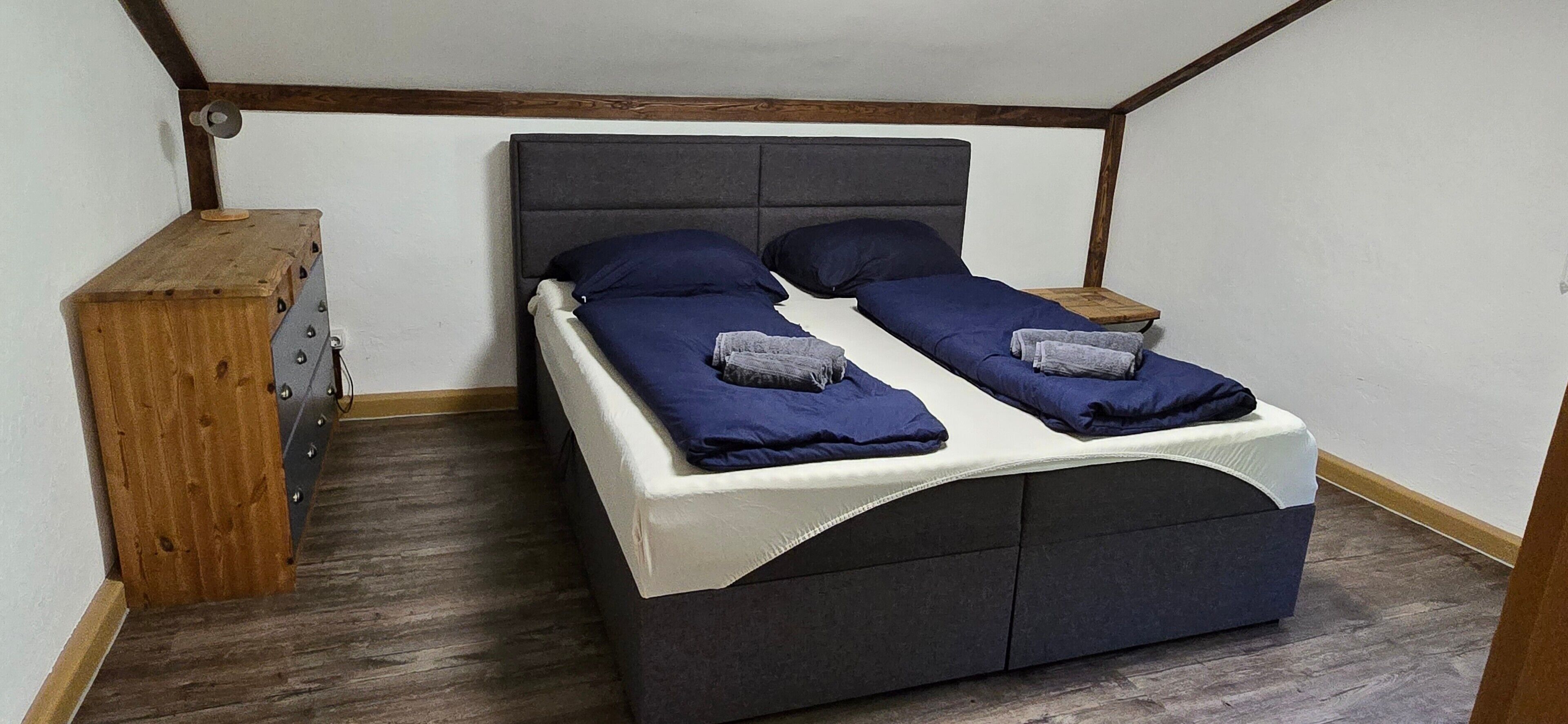 Un lit simple avec une tête de lit et un pied de lit de couleur sombre, deux oreillers et un couvre-lit blanc.