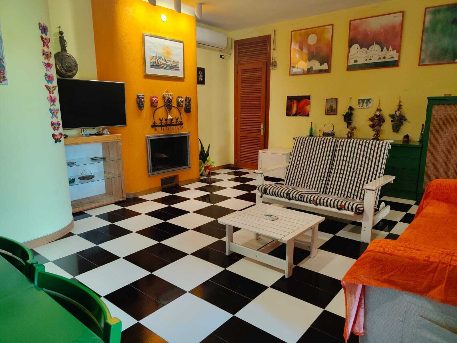 A room with a checkered floor, a television, a sofa, and various wall decorations.