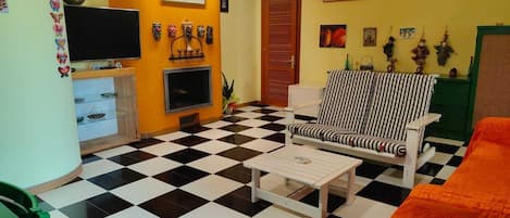 A room with a checkered floor, a television, a sofa, and various wall decorations.