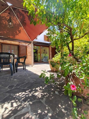 A covered outdoor seating area with stone flooring, a potted plant, and a bench. - Villa Gioirisia. A retreat for relaxation and nature. X4 (Campania)