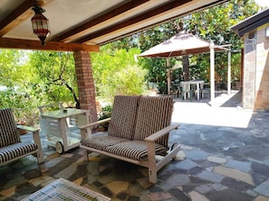 An outdoor patio with a stone floor, a covered seating area, and a view of greenery. - Villa Gioirisia. A retreat for relaxation and nature. X4 (Campania)