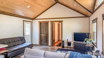 A spacious living room with a high ceiling, a fireplace, a television, and a sofa.