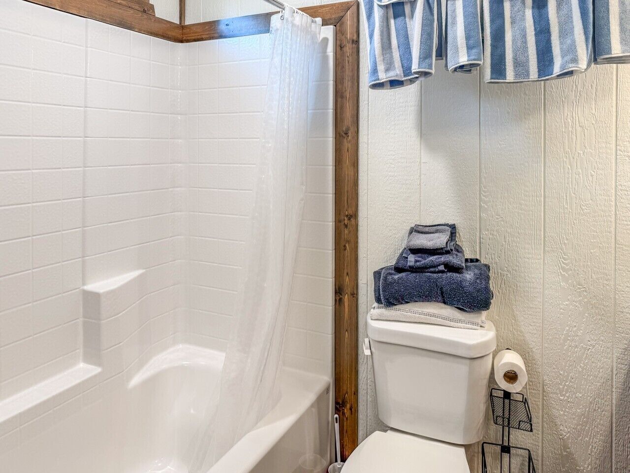 Een badkamer met een wit bad, een toilet en een handdoekrek met handdoeken.
