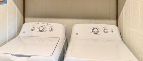Two front-loading washing machines in a laundry area with wooden cabinets above.
