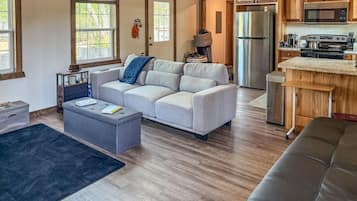 A spacious living area with a sofa, a coffee table, and a kitchen area with a refrigerator and microwave.