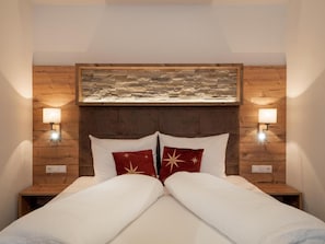 A hotel room with a wooden headboard, two bedside lamps, and a framed artwork above the bed.