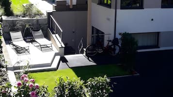Un edificio moderno a due piani con tetto piatto, ampie finestre e un’area salotto esterna coperta con sedie e tavoli.