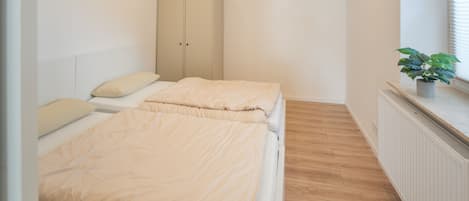 Un dormitorio con dos camas, un armario, un radiador y una planta en maceta.