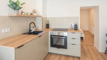 Een kleine keuken met een inbouwoven, een spoelbak en een aanrecht.