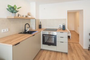 Une cuisine compacte dotée d’un four encastré, d’un évier et d’un plan de travail.