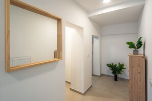 Un couloir avec un miroir encadré en bois, un radiateur, une plante en pot et un meuble en bois.