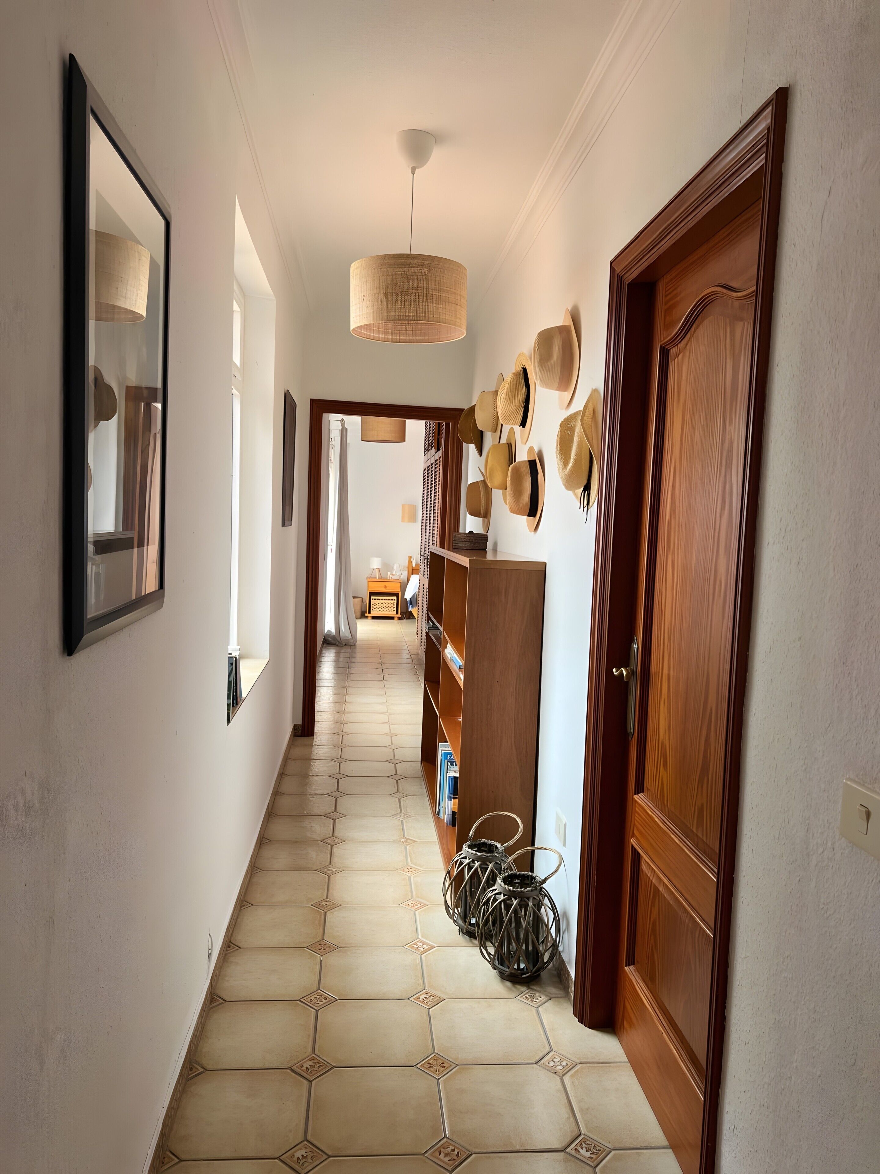 Un pasillo con suelo de baldosas, puertas de madera y un perchero en la pared.