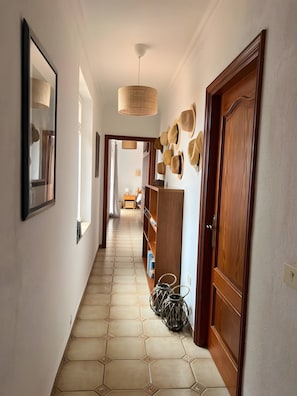 Un pasillo con suelo de baldosas, puertas de madera y un perchero en la pared.