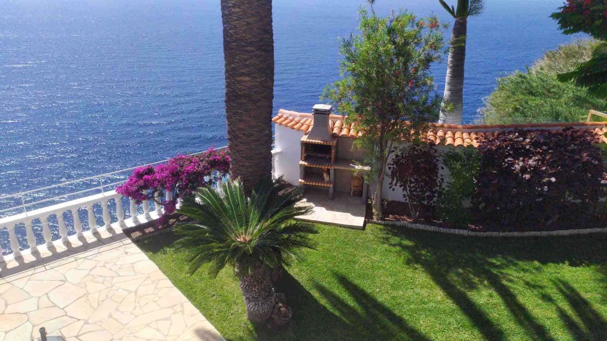 Una propiedad costera con un camino de piedra, un pequeño patio y vistas al mar.