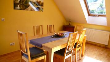 A dining area with a wooden table, chairs, and a painting on the wall.