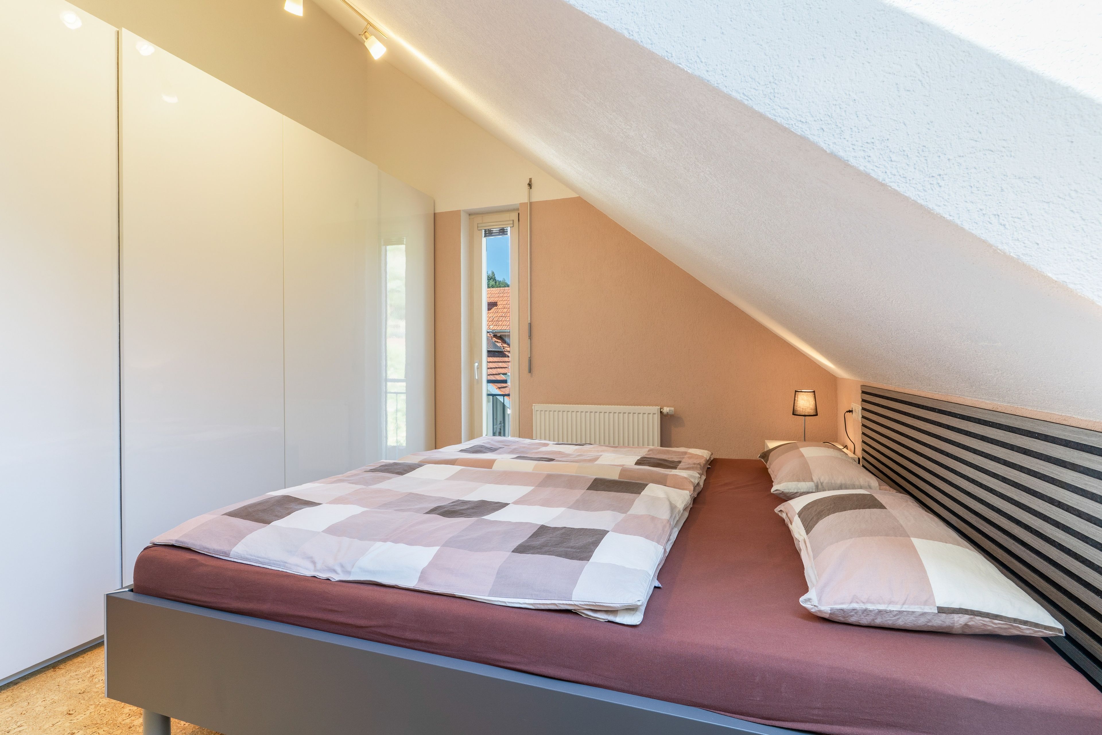 A bedroom with a bed, a radiator, and a window.