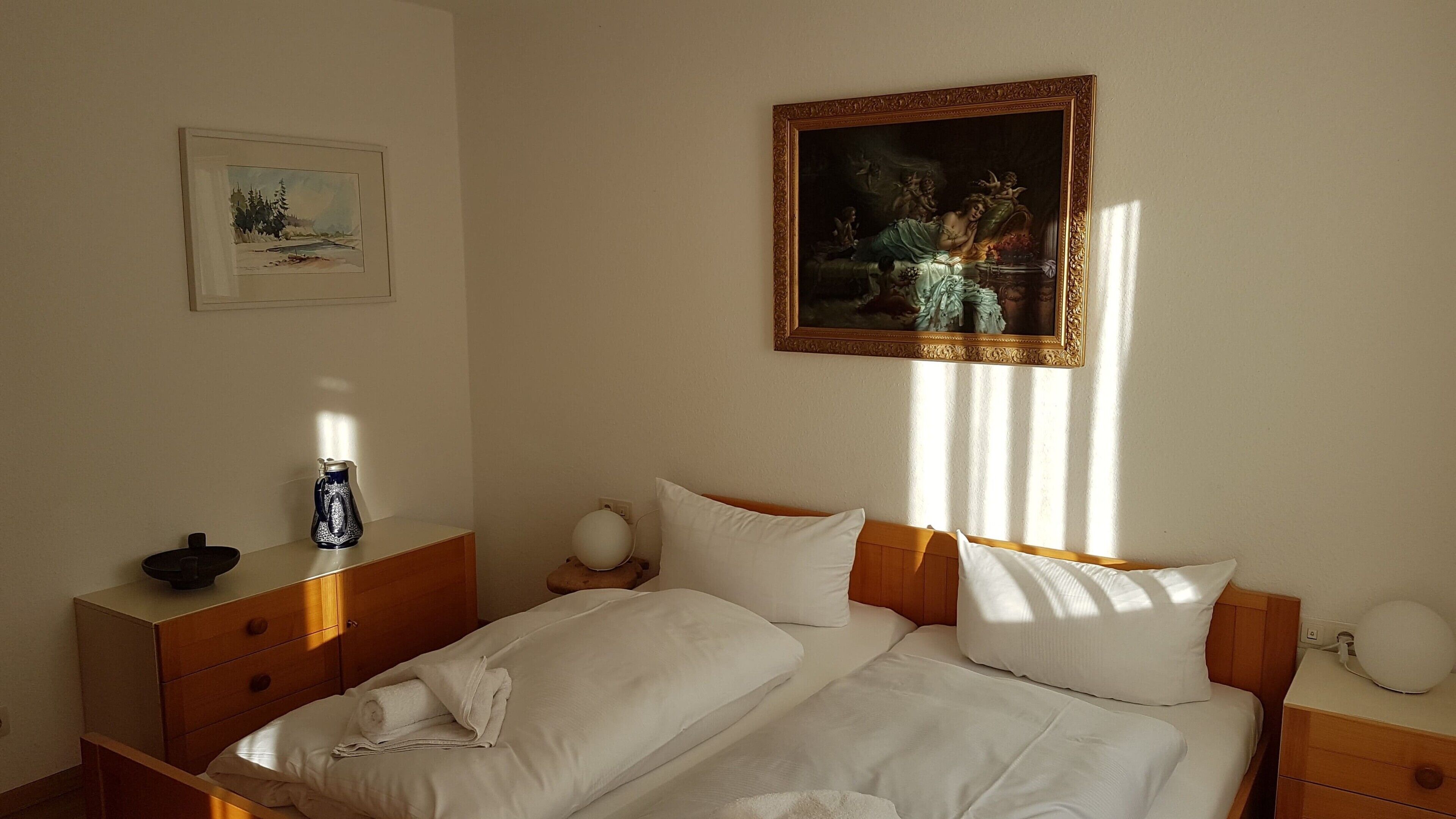 Ein Hotelzimmer mit einem Bett, Nachttischen, einem Bild und einem Fenster.