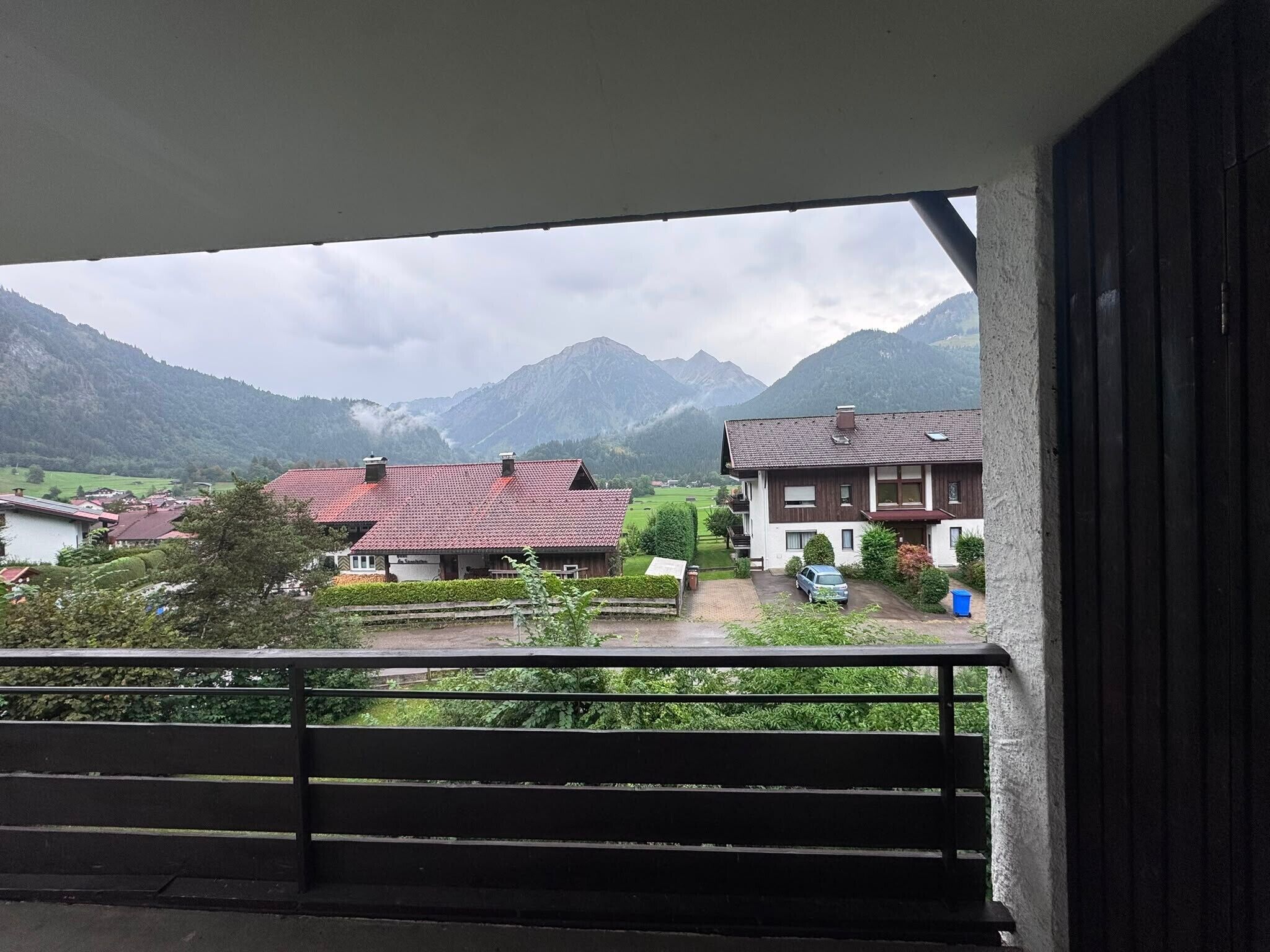 A balcony with a view of a mountain range and residential buildings.