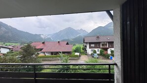Un balcón con vistas a una cadena montañosa y edificios residenciales.