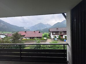 A balcony with a view of a mountain range and residential buildings.