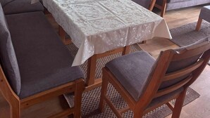 Un comedor con una mesa dispuesta para cuatro personas, rodeada de sillas de madera con cojines grises.