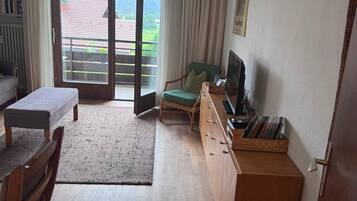 A living room with a sofa, a coffee table, a TV, and a bookshelf.