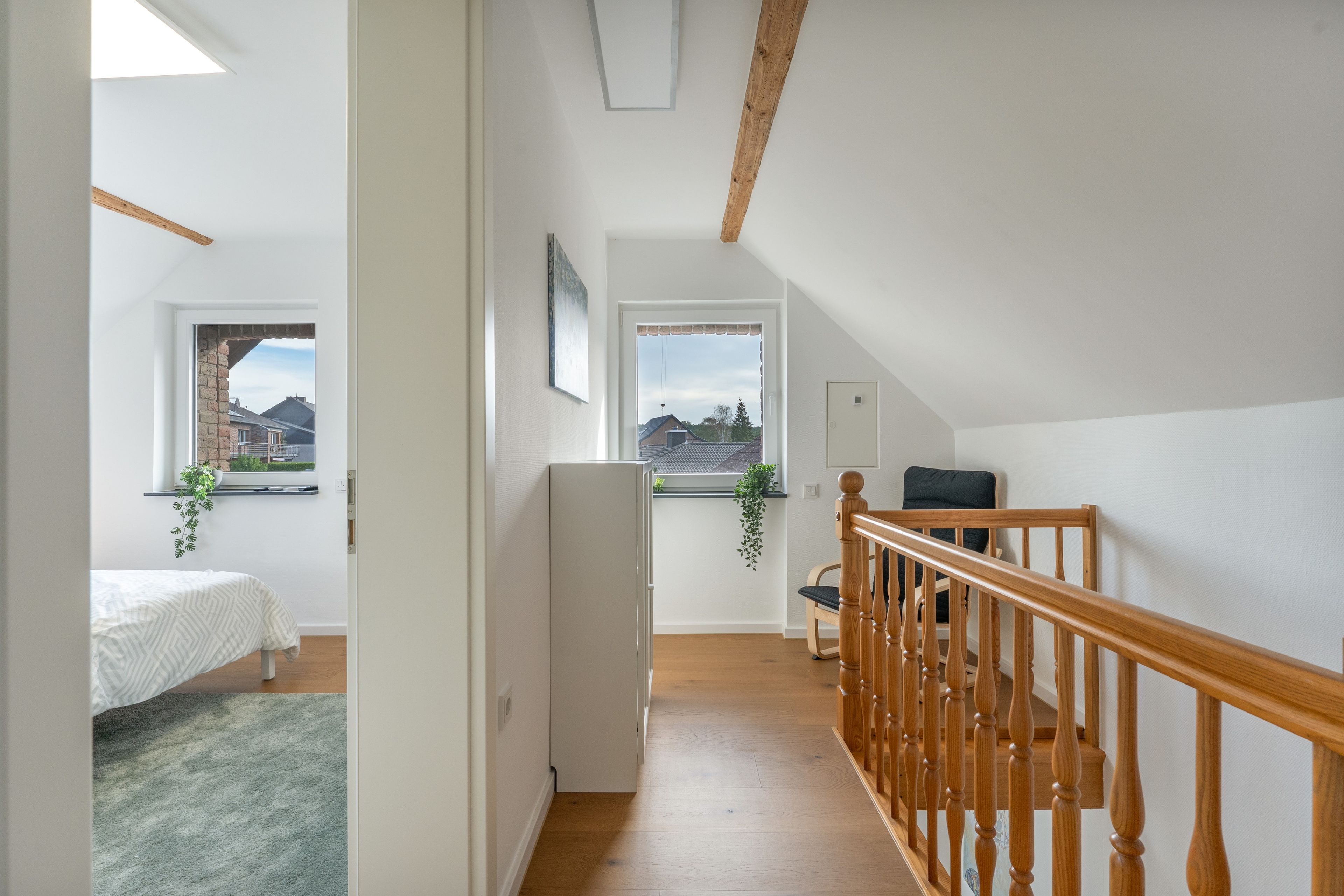 A narrow hallway with a wooden staircase leading to a loft bedroom.