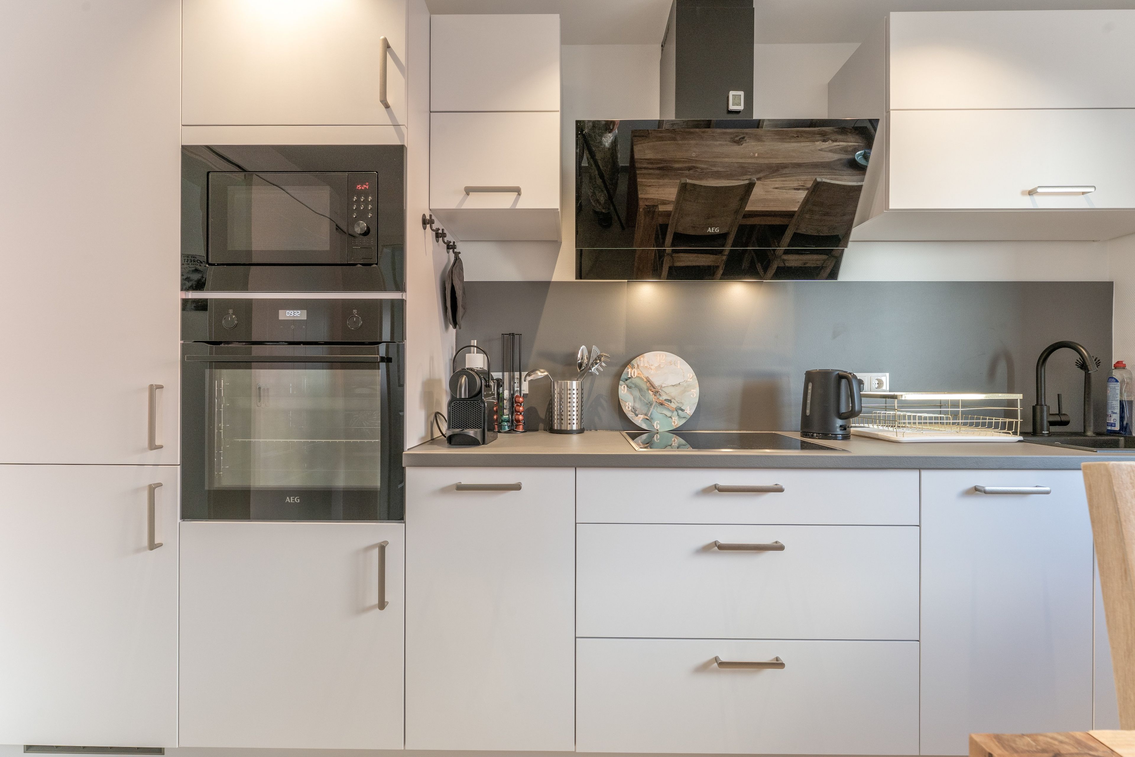 Una cocina moderna con electrodomésticos integrados, techo de madera y un reloj decorativo.