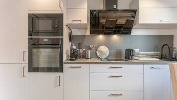 Una cocina moderna con electrodomésticos integrados, techo de madera y un reloj decorativo.