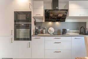 Une cuisine moderne dotée d’appareils électroménagers intégrés, d’un plafond en bois et d’une horloge décorative.