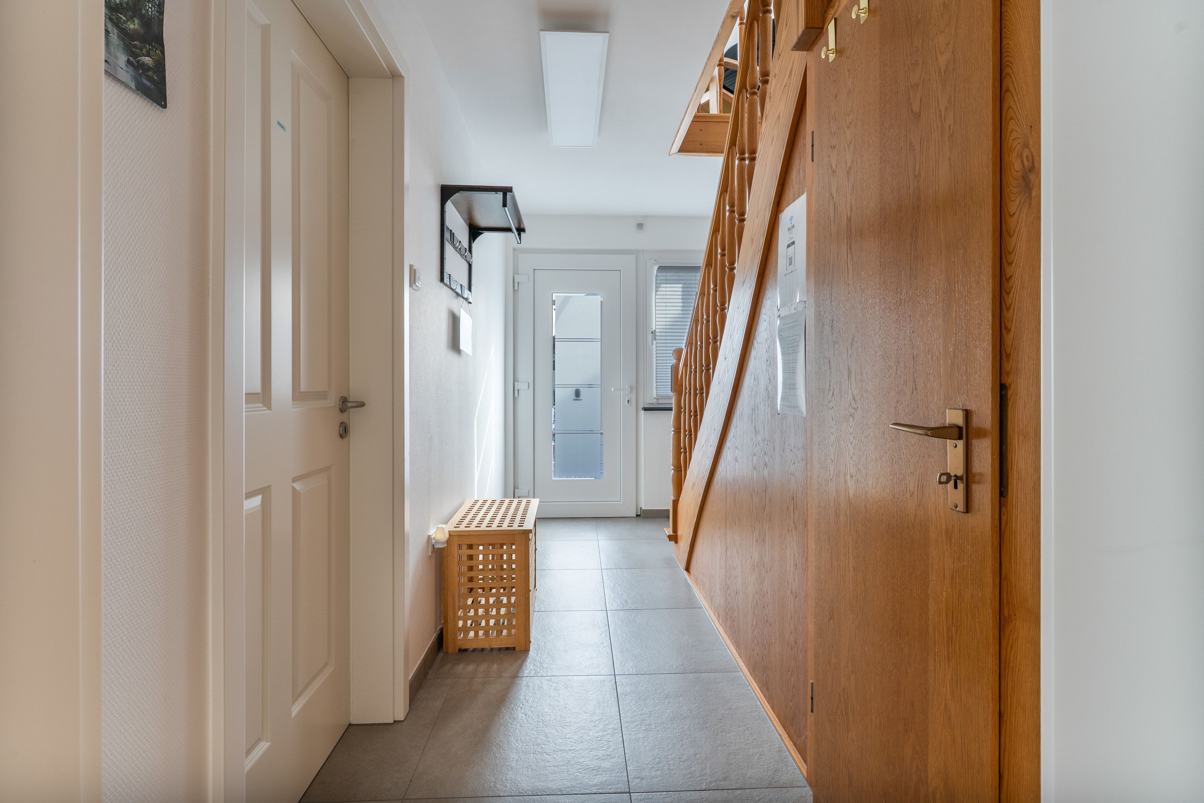 A hallway with wooden doors, a small wooden basket, and a door with a window.