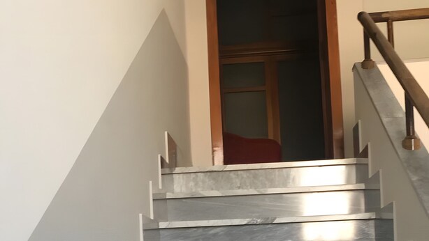A staircase with a wooden handrail and a door at the top.