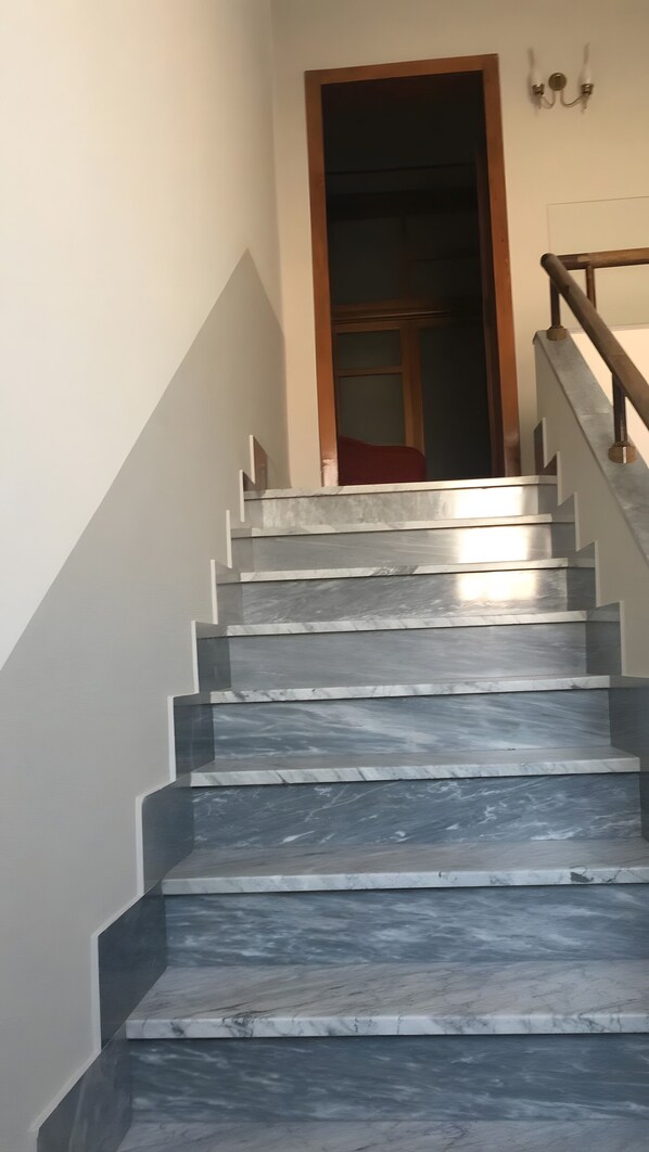 A staircase with a wooden handrail and a door at the top.