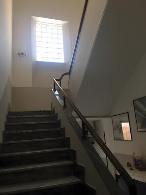 Una escalera con barandilla y un ventanal en la parte superior.