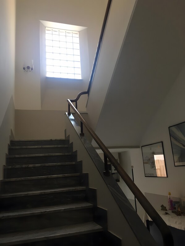 Una escalera con barandilla y un ventanal en la parte superior.