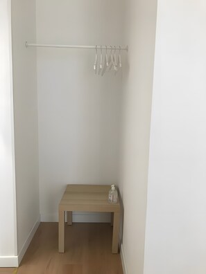 Una habitación pequeña y vacía con un banco de madera, una pared blanca y un perchero de metal.