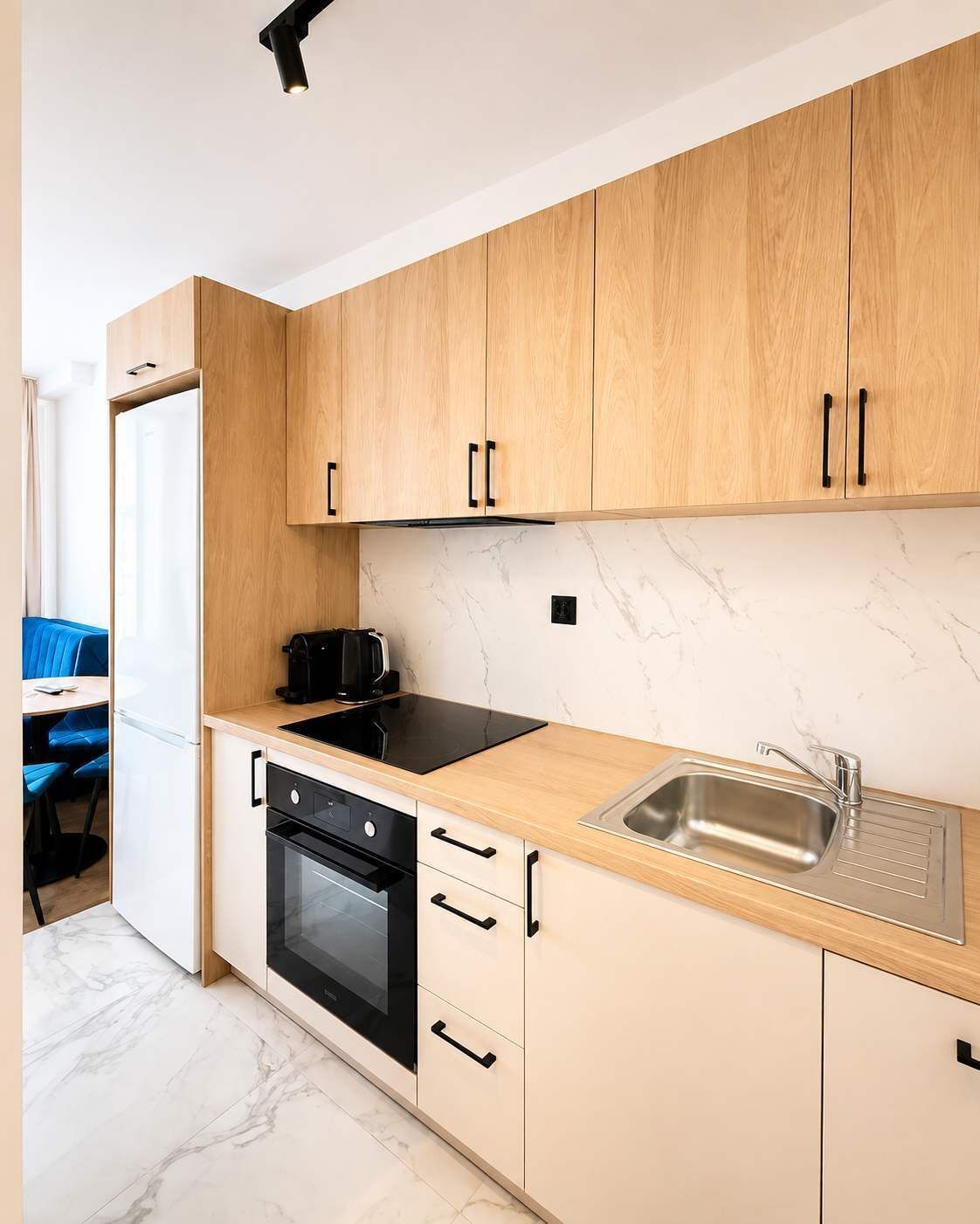 A modern kitchen with wooden cabinets, a black stove, a sink, and a marble backsplash.